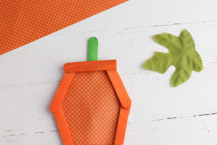 Green popsicle stick attached to the top of an orange popsicle stick pumpkin to create the stem