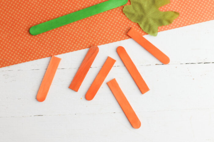 Orange popsicle sticks cut into pieces for making a popsicle stick pumpkin craft