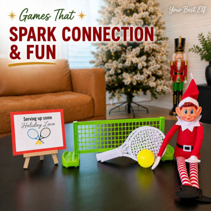 Christmas elf game setup featuring mini tennis rackets, ball, net, and a “Serving Up Some Holiday Love” sign beside a decorated Christmas tree.